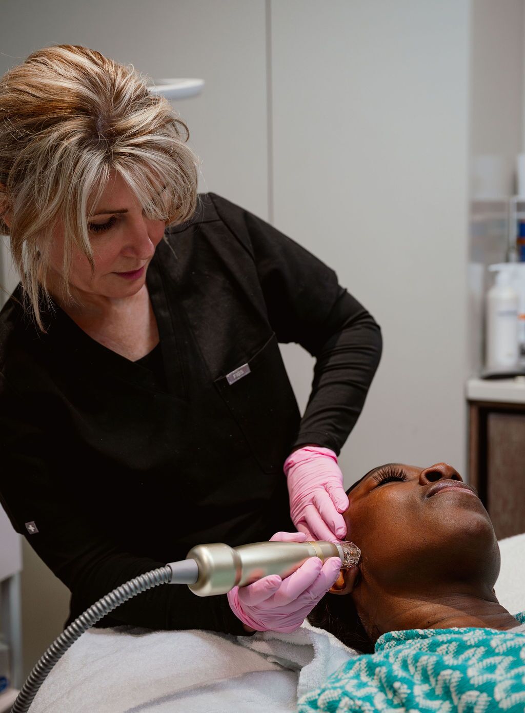 An African-American man relaxes on a treatment table while an Artisan provider delivers Sylfirm X Atlanta microneedling on his cheek.